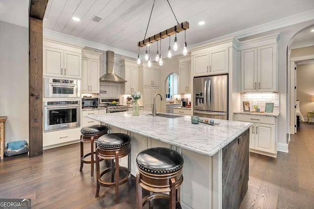 kitchen with a sink, visible vents, appliances with stainless steel finishes, wall chimney exhaust hood, and crown molding