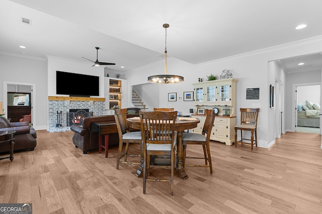 dining space with stairway, recessed lighting, crown molding, a brick fireplace, and light wood-type flooring