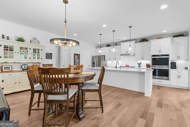 dining space featuring crown molding, light wood-style flooring, and recessed lighting