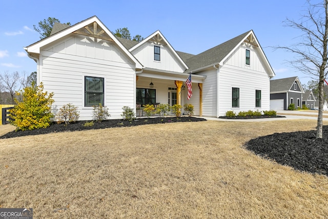 modern inspired farmhouse featuring a garage, covered porch, board and batten siding, and a front yard