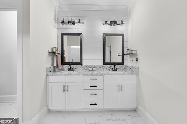 full bathroom with baseboards, double vanity, ornamental molding, marble finish floor, and a sink