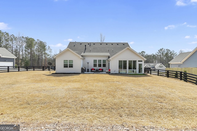 rear view of house featuring a lawn, a shingled roof, a sunroom, and fence