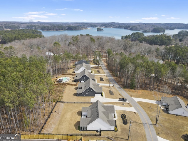 birds eye view of property featuring a water view and a wooded view