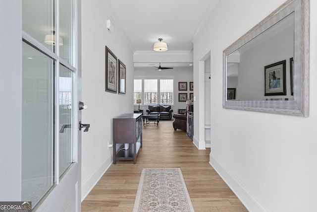 hallway featuring crown molding, baseboards, and wood finished floors