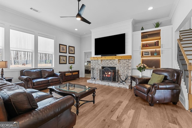 living area featuring stairway, ceiling fan, crown molding, and light wood finished floors