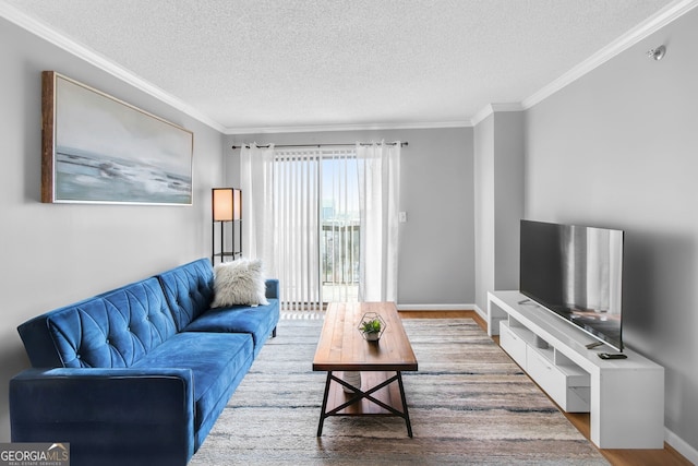 living area with ornamental molding, a textured ceiling, baseboards, and wood finished floors