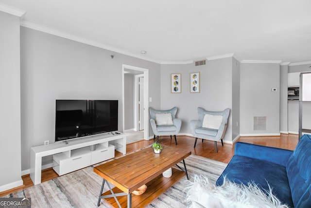 living room with ornamental molding, visible vents, baseboards, and wood finished floors