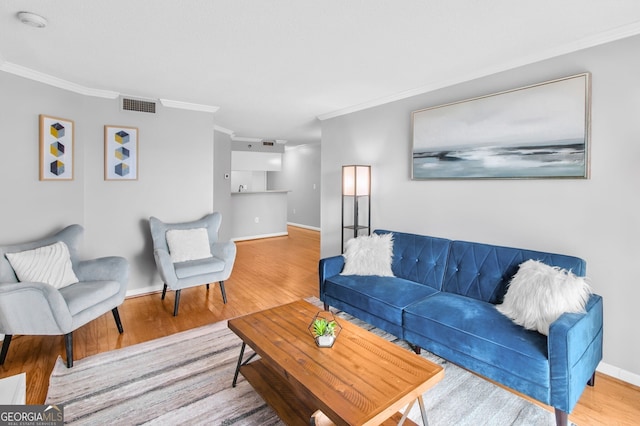 living room with ornamental molding, visible vents, baseboards, and wood finished floors