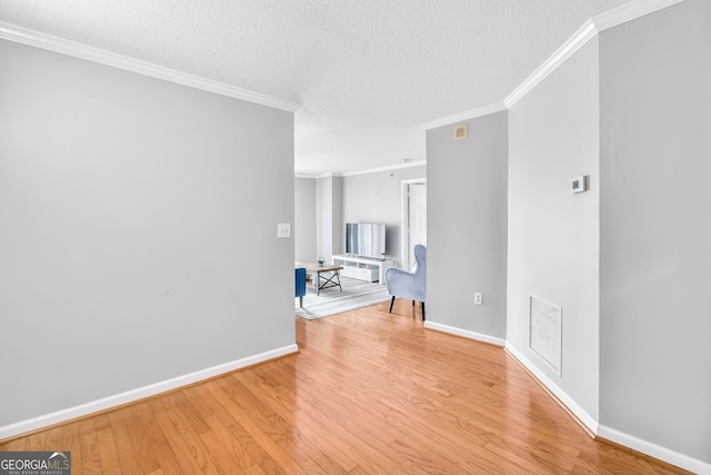 interior space with light wood-style floors, visible vents, crown molding, and a textured ceiling