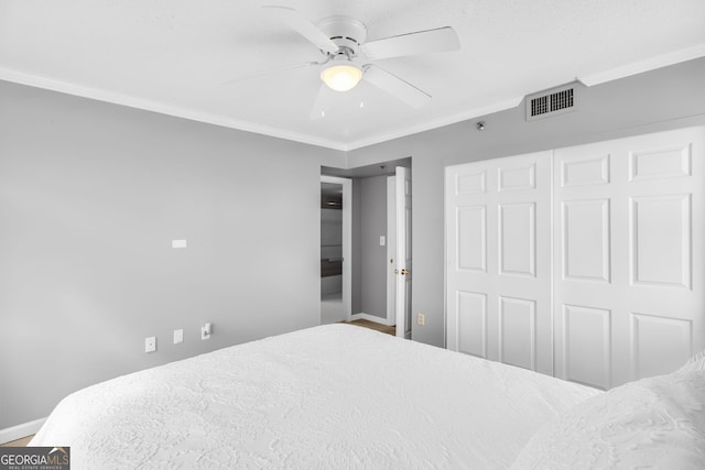 bedroom featuring baseboards, visible vents, ceiling fan, crown molding, and a closet