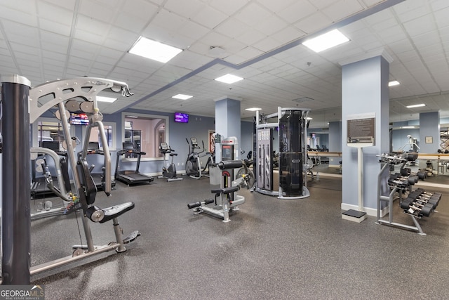 exercise room featuring a drop ceiling and baseboards