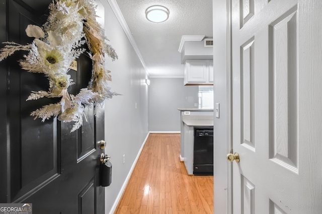 corridor with crown molding, visible vents, a textured ceiling, light wood-type flooring, and baseboards