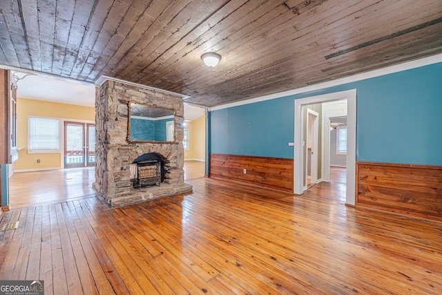 unfurnished living room featuring a wainscoted wall, crown molding, wood ceiling, wood walls, and hardwood / wood-style floors