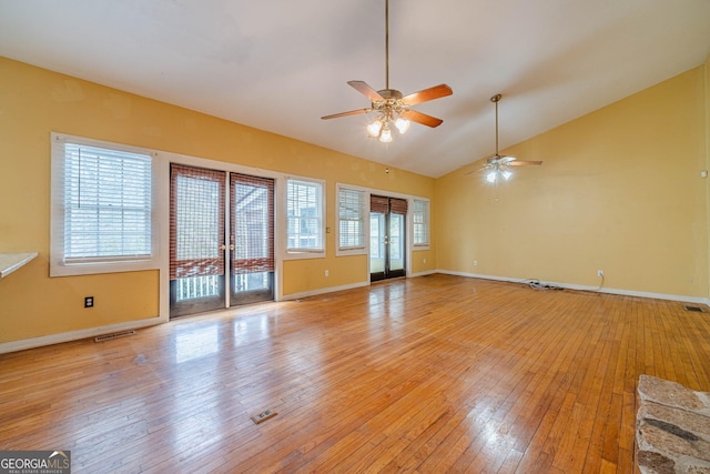 unfurnished living room with visible vents, plenty of natural light, lofted ceiling, and light wood-style flooring