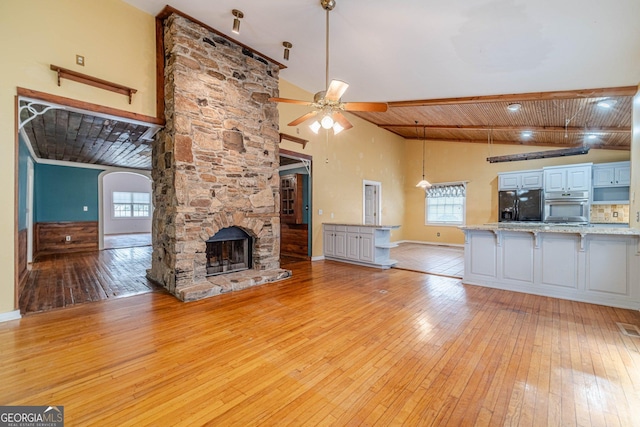 unfurnished living room featuring a healthy amount of sunlight, light wood finished floors, and a stone fireplace