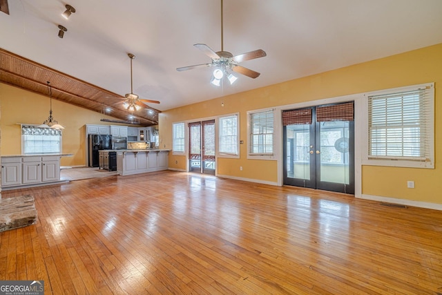 unfurnished living room with visible vents, baseboards, lofted ceiling, french doors, and light wood-type flooring