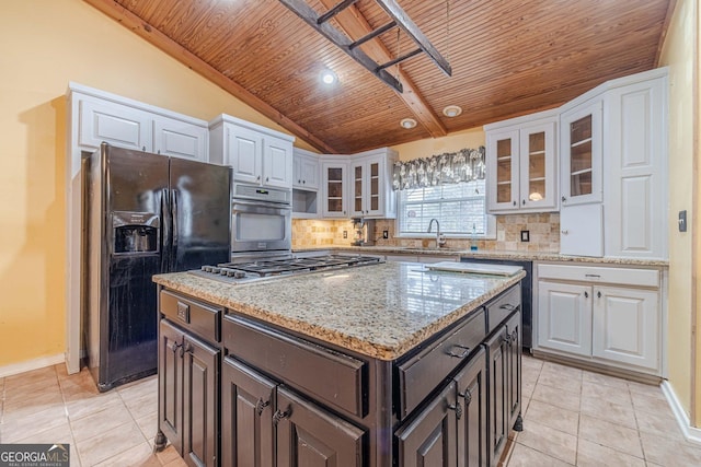 kitchen with appliances with stainless steel finishes, a sink, backsplash, and light tile patterned floors