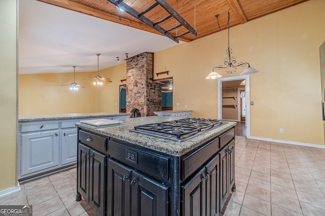 kitchen with wooden ceiling, a center island, beamed ceiling, decorative light fixtures, and stainless steel gas stovetop