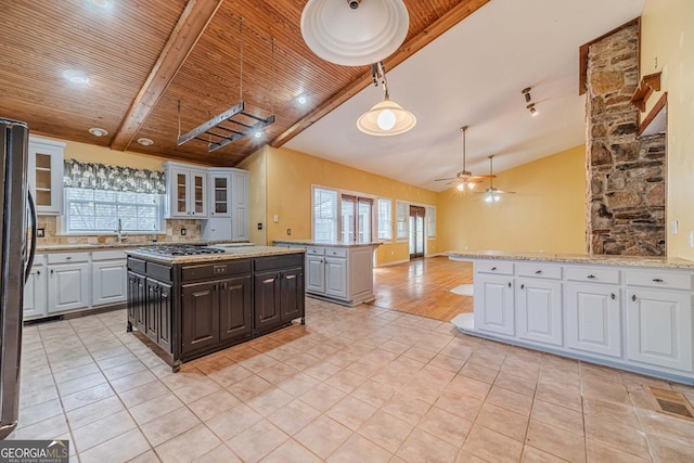 kitchen featuring wooden ceiling, light tile patterned floors, glass insert cabinets, and stainless steel gas cooktop