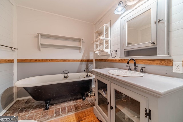 bathroom with wood finished floors, a freestanding tub, vanity, and crown molding