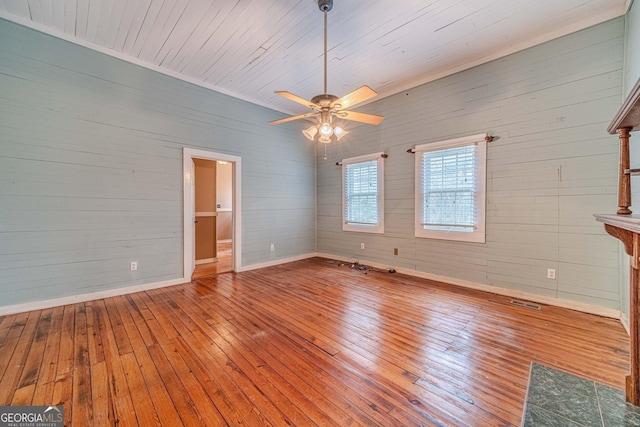 unfurnished living room with hardwood / wood-style flooring, ceiling fan, visible vents, and baseboards