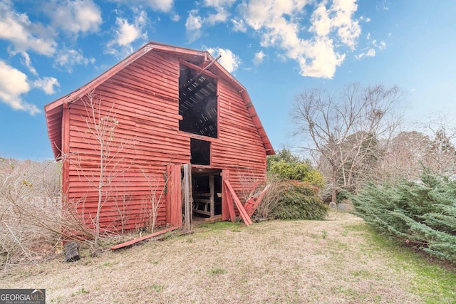 view of home's exterior featuring an outdoor structure, a barn, and a lawn