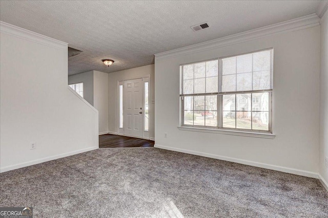 entrance foyer featuring a textured ceiling, visible vents, baseboards, ornamental molding, and dark colored carpet