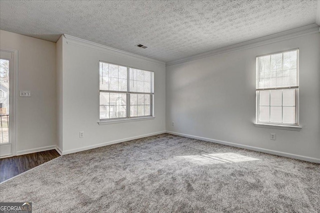 carpeted empty room with baseboards, plenty of natural light, visible vents, and crown molding