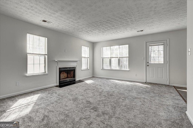 unfurnished living room with carpet floors, a high end fireplace, and visible vents