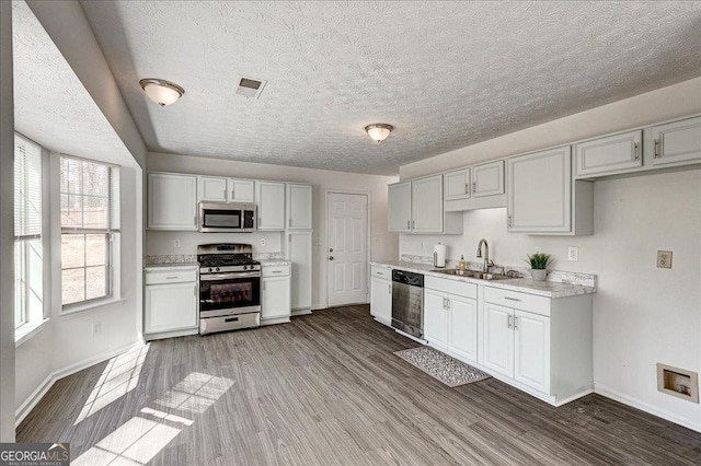 kitchen with wood finished floors, a sink, visible vents, light countertops, and appliances with stainless steel finishes