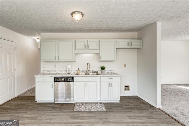 kitchen with stainless steel dishwasher, light countertops, a sink, and wood finished floors