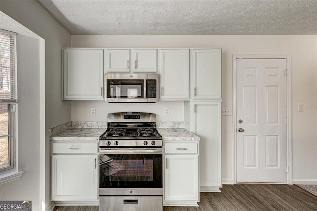 kitchen featuring a textured ceiling, stainless steel appliances, wood finished floors, and white cabinets