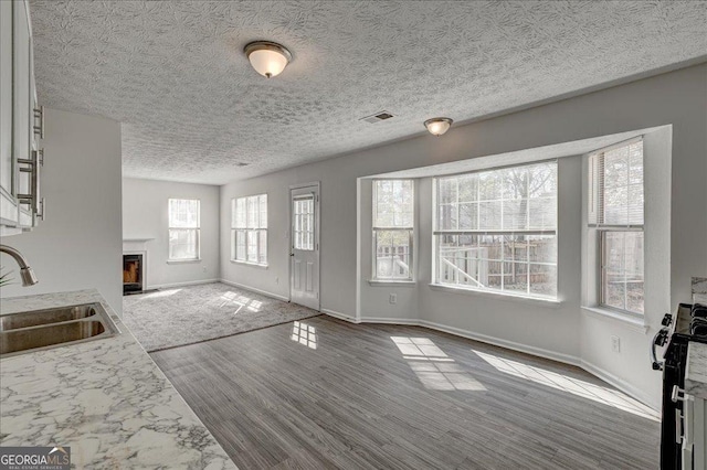 unfurnished living room featuring baseboards, a fireplace, visible vents, and a sink