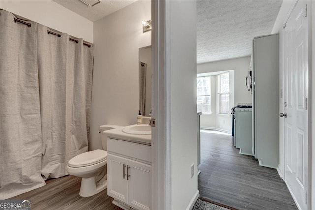 bathroom with toilet, a textured ceiling, wood finished floors, and vanity