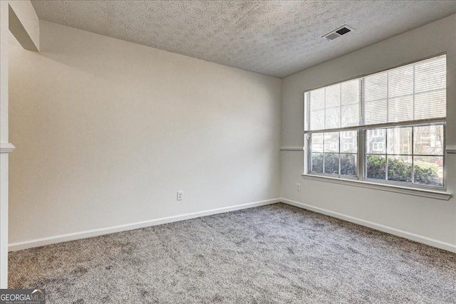 carpeted spare room featuring visible vents, a textured ceiling, and baseboards