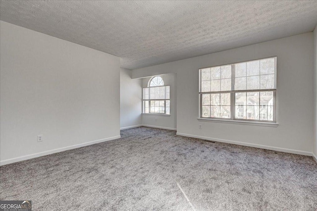 empty room featuring carpet floors, a textured ceiling, and baseboards