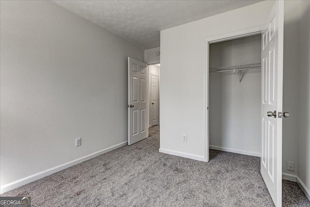 unfurnished bedroom featuring a textured ceiling, a closet, carpet, and baseboards