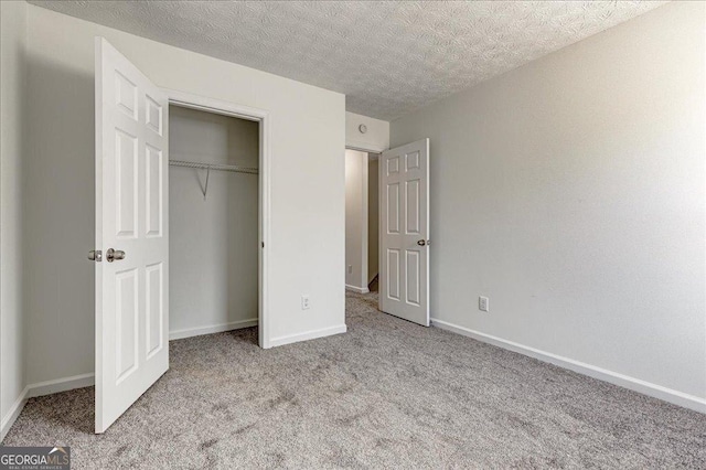 unfurnished bedroom with a textured ceiling, a closet, carpet, and baseboards