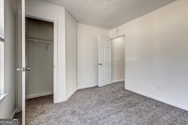 unfurnished bedroom featuring carpet floors, a closet, baseboards, and a textured ceiling