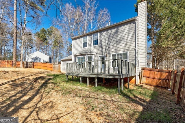 rear view of property with a fenced backyard, a chimney, and a wooden deck