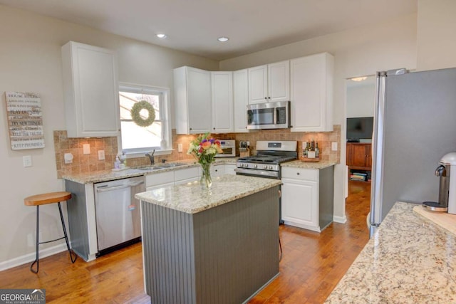 kitchen featuring tasteful backsplash, light wood-style flooring, appliances with stainless steel finishes, and white cabinets