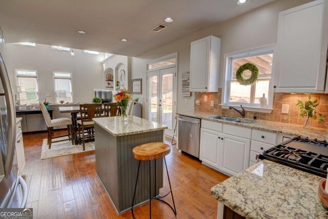 kitchen featuring french doors, stainless steel appliances, visible vents, a sink, and a kitchen island