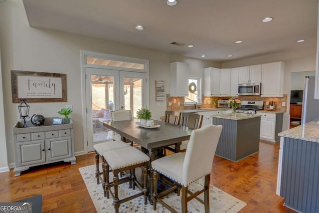 dining area featuring french doors, wood finished floors, and a healthy amount of sunlight