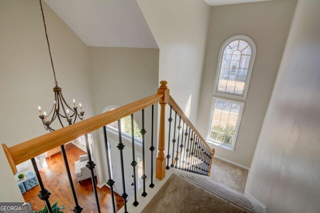 stairs featuring a chandelier, a high ceiling, wood finished floors, and baseboards