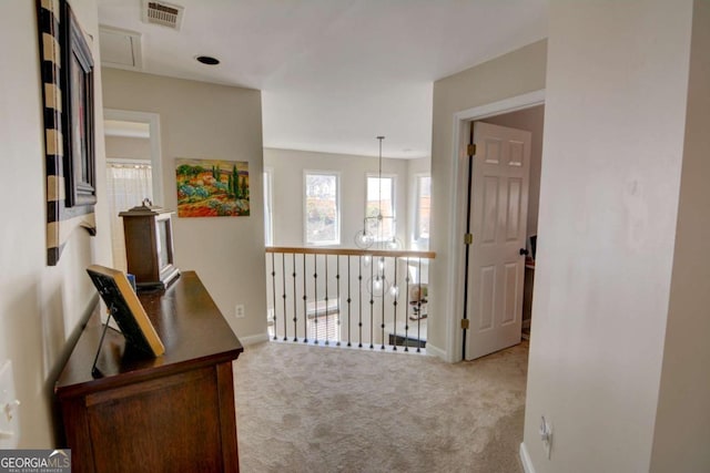 hallway with attic access, carpet, visible vents, and baseboards