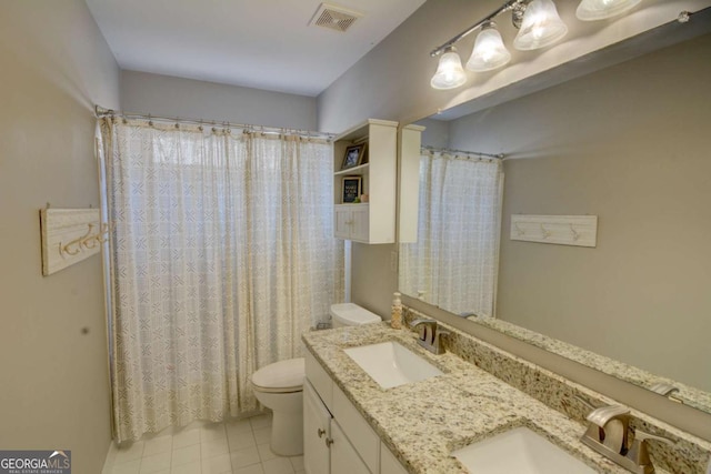 bathroom featuring toilet, double vanity, a sink, and visible vents