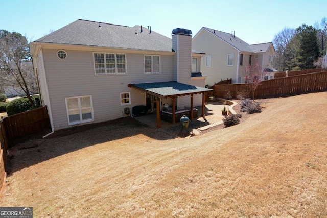 rear view of house with a patio, a chimney, fence, and roof with shingles