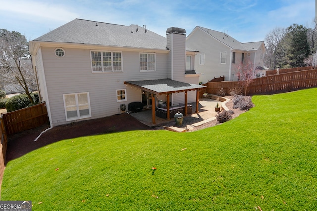 rear view of house featuring a chimney, a lawn, a patio area, and a fenced backyard