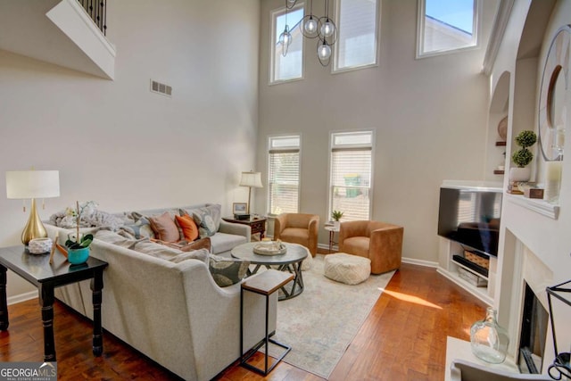 living room with hardwood / wood-style flooring, an inviting chandelier, visible vents, and baseboards