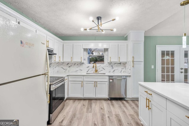 kitchen featuring under cabinet range hood, stainless steel appliances, a sink, white cabinetry, and light countertops